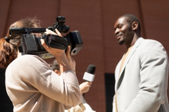Mulher filmando e entrevistando homem